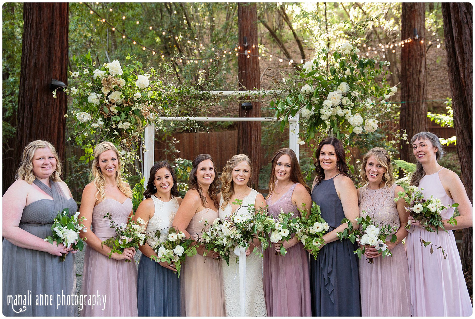 Bride and bridesmaids hold garden bouquets beneath the redwoods at Deer Park Villa