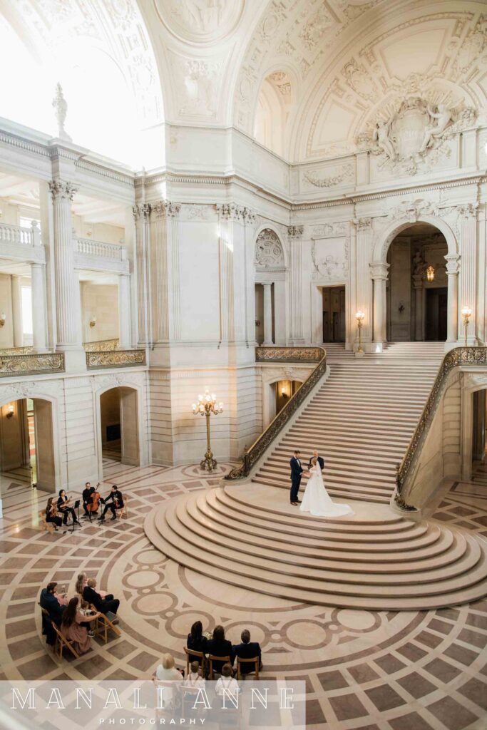 A couple gets married on the grand staircase during a private Saturday rental of the entire San Francisco City Hall